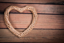 A heart shaped wreath on a wooden table.