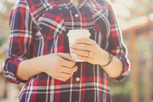 woman in a plaid shirt holding a cup of coffee 