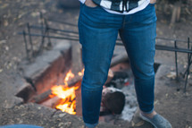 a woman standing by a fire 