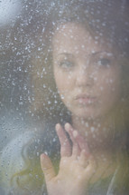 Woman looking out a frosted window.