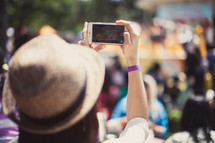 woman in a straw hat taking a picture with her cellphone 
