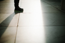feet standing in sunlight on a marble floor 