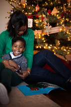 mother and son reading a book near a Christmas tree 