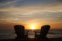 pair of adirondack chairs on a beach 