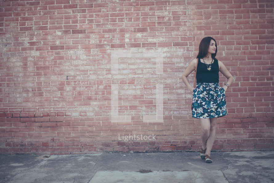a woman posing in front of a brick wall 