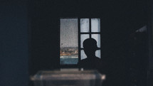 silhouette of a man in a ball cap in front of a window 