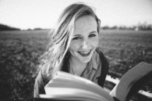 teen girl reading a Bible outdoors smiling