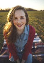 smiling teen girl with braces sitting on a blanket