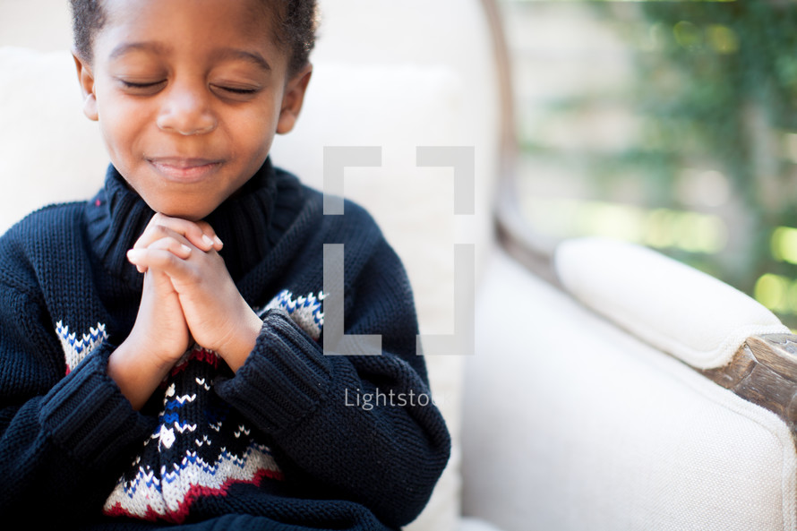 a boy child with praying hands 
