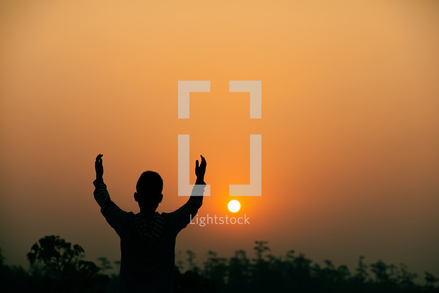 silhouette with raised hands at sunset 