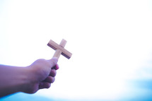 Hand holding a wooden cross up to the sky