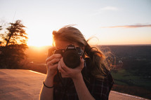 a woman with a camera at sunset 