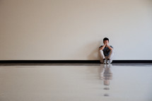 a sad man sitting against a wall 