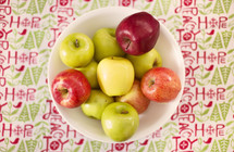 red and green apples in a bowl and Christmas table cloth 