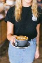 woman holding cappuccino in a mug 