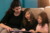 a mother reading to her daughters 