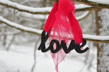 Letters spelling "love" hanging from a snow-covered tree.