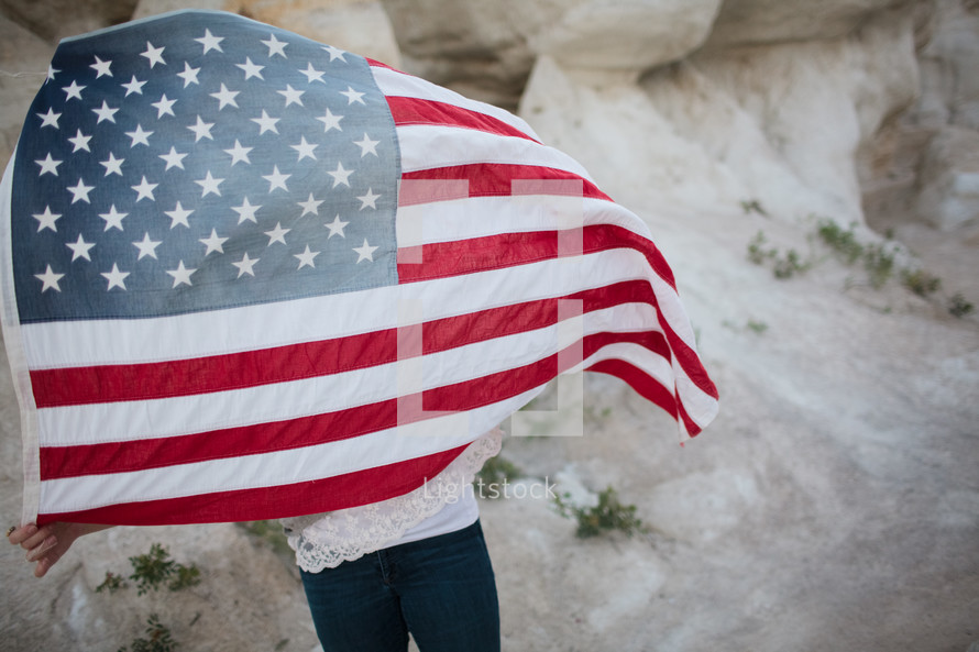  a woman walking carrying an American flag on her back 