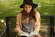woman sitting on a park bench reading a Bible 
