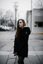 a young woman walking down a street and stopping to look at the camera 