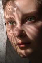 sunlight on the face of a child through lace curtains 