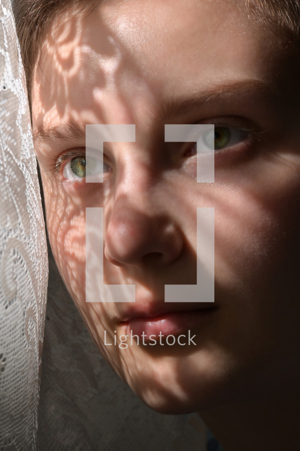 sunlight on the face of a child through lace curtains 