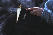 a girl sitting on a bed reading a Bible 