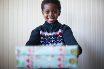 a boy child holding a wrapped Christmas girt 