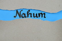 Nahum - torn open kraft paper over blue paper with the name of the prophetic book Nahum