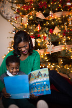 mother and son reading a book near a Christmas tree