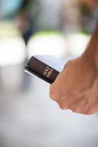 hand holding a Bible and bulletin 