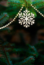 a snowflake ornament and beads on a Christmas tree 