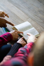 Hands pointing at a scripture verse in an open Bible