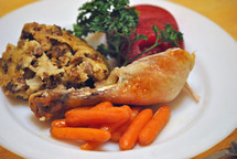 Holiday dinner: roast chicken, carrots, dressing, and spiced apples with a parsley garnish.