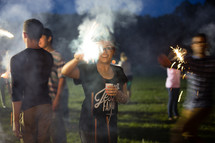 Group of teens holding sparklers with smoke.