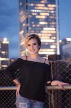 a young woman posing in front of city buildings at night 