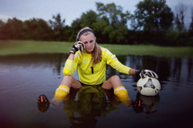 Girl sitting in a pool of water with a soccer ball.