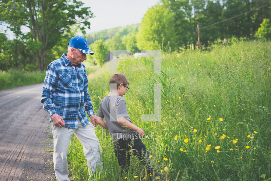 grandfather and boy walking down a gravel road 