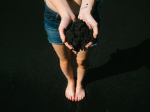 A woman holds a handful of soil.