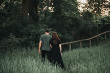 a couple walking through tall grasses 