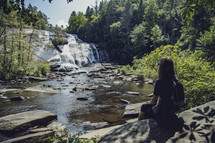 woman sitting watching a waterfall 