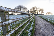 Curved path along a snowy fence and field