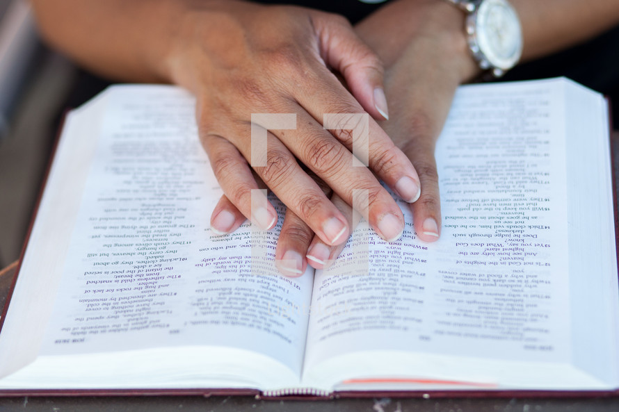 hands on the pages of a Bible 