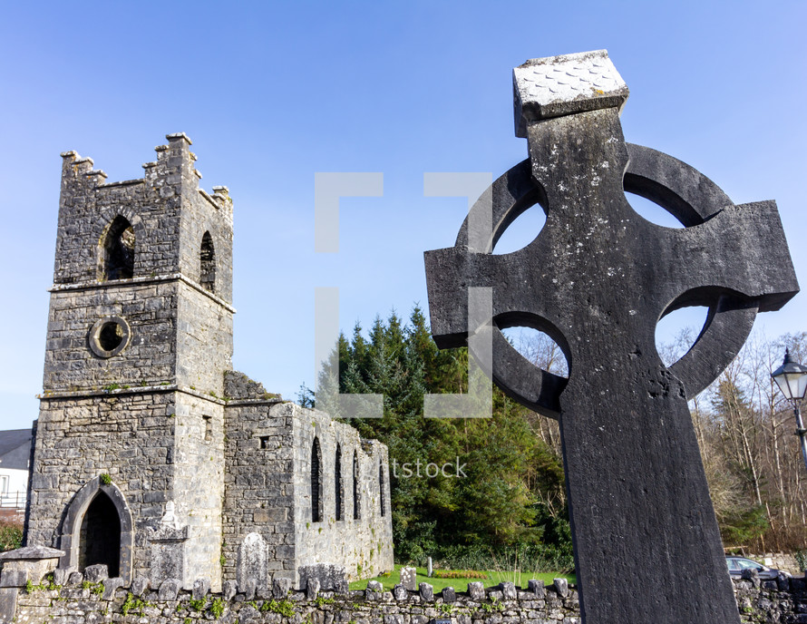 Gravestone in the shape of a Celtic cross with Saint Mary of the Rosary Catholic church in the background near Cong, County Mayo, Ireland