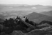 a man and woman sitting on a mountain top 