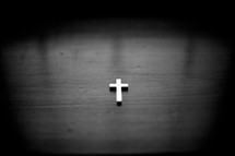 Cross pendant on a wood table.
