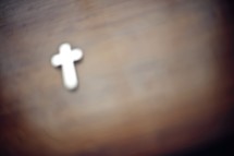 Cross pendant on a wood table.