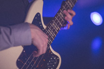 man's hands playing a bass.