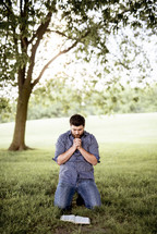 a man kneeling reading a Bible 