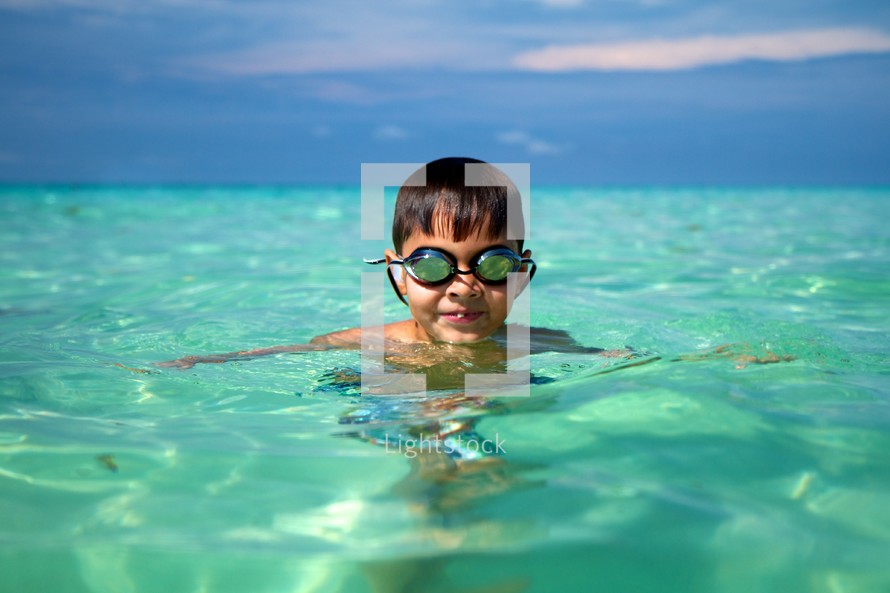 A young boy wearing goggles in the ocean